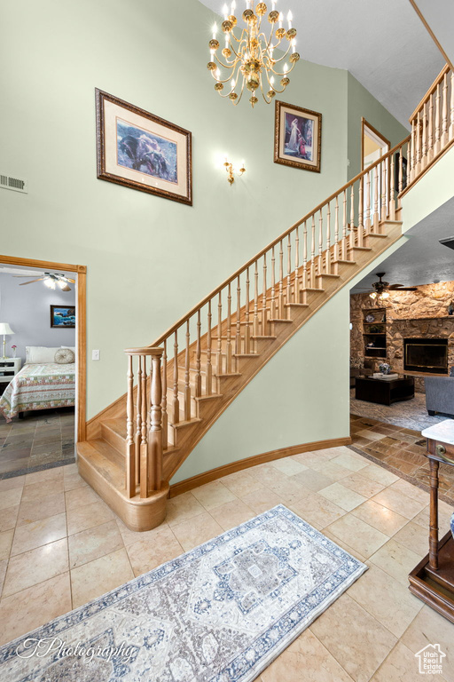 Stairs with visible vents, a towering ceiling, and ceiling fan with notable chandelier