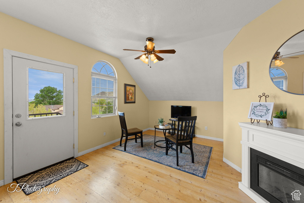 Office space with wood-type flooring, a glass covered fireplace, lofted ceiling, baseboards, and ceiling fan