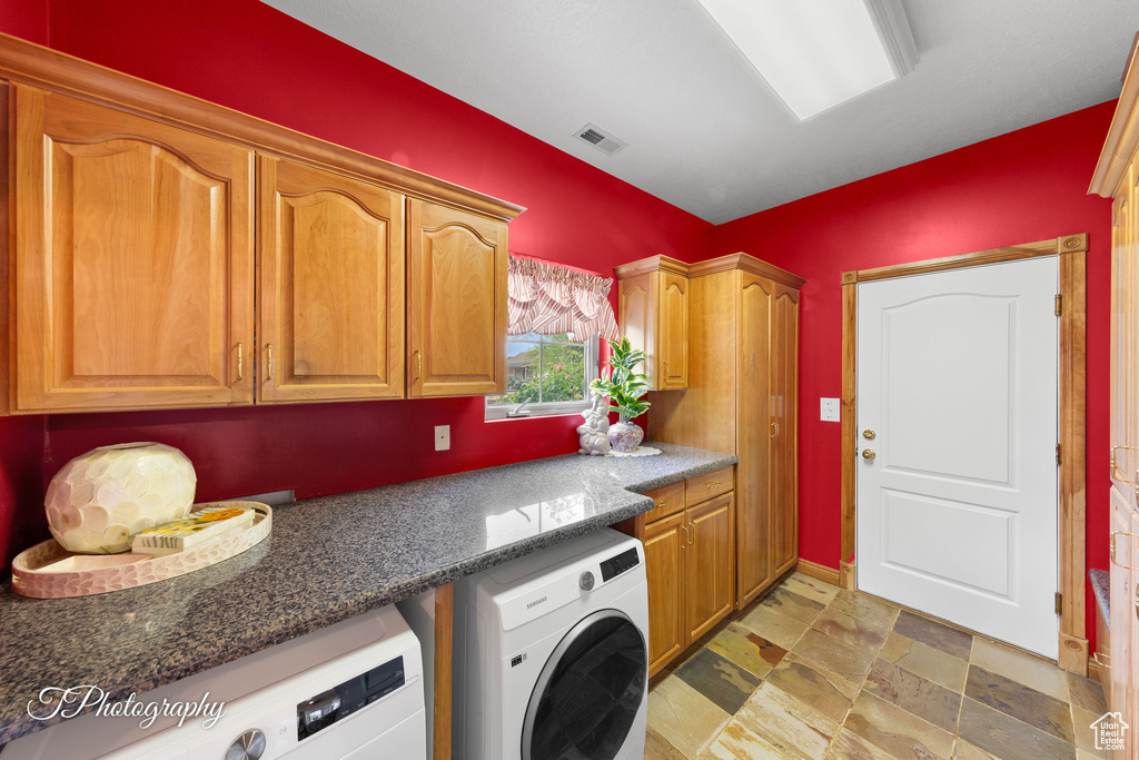 Laundry room with cabinet space, stone finish floor, washer and clothes dryer, and visible vents