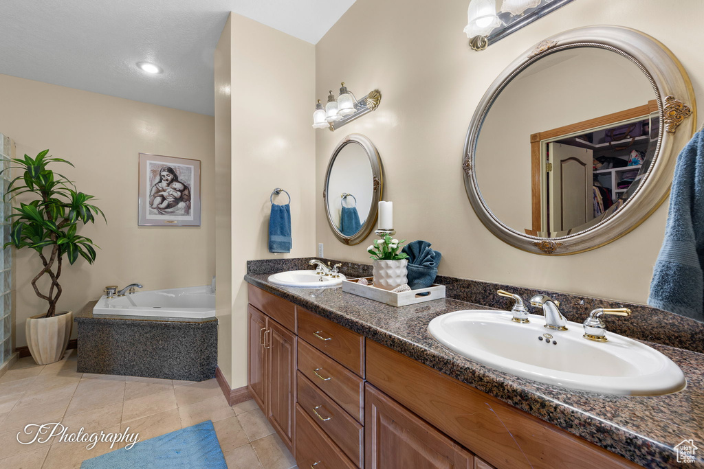Full bath featuring double vanity, a sink, a garden tub, and tile patterned floors