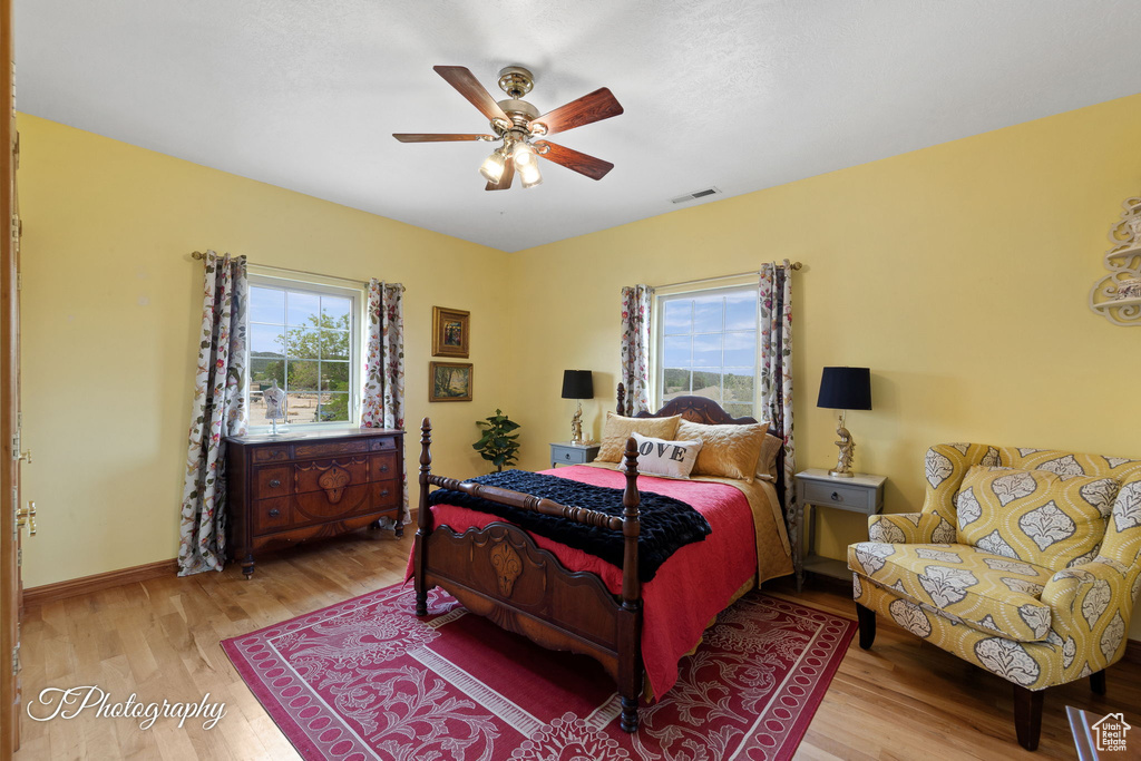 Bedroom featuring a ceiling fan, baseboards, visible vents, and wood finished floors