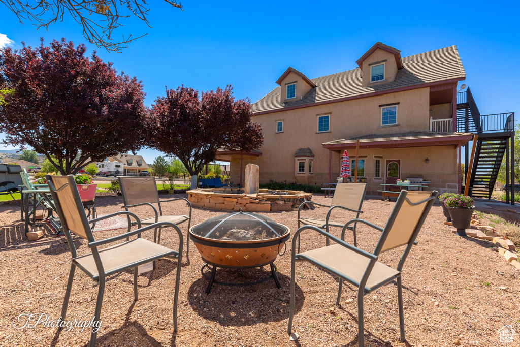 Rear view of property featuring a patio, an outdoor fire pit, stucco siding, and stairway