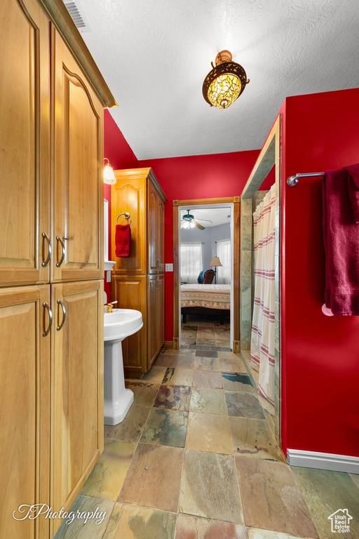 Ensuite bathroom featuring ceiling fan, a shower with shower curtain, stone tile floors, ensuite bathroom, and visible vents