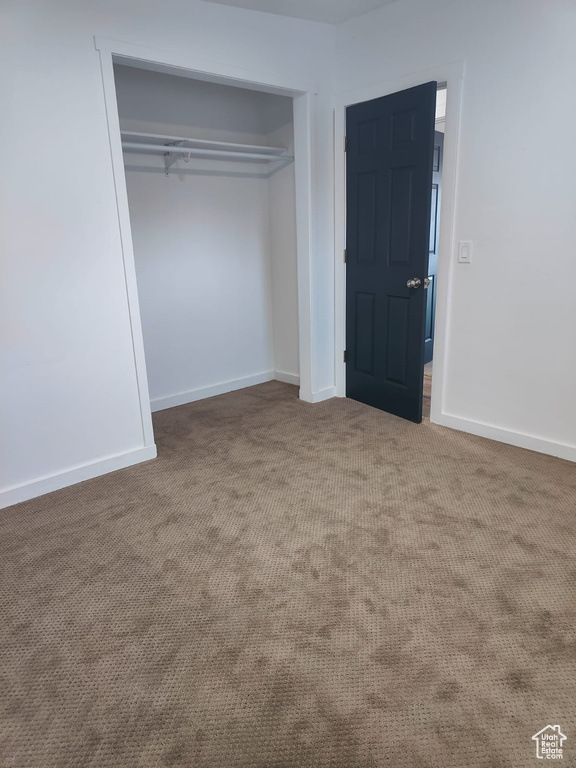 Unfurnished bedroom featuring carpet, a closet, and baseboards