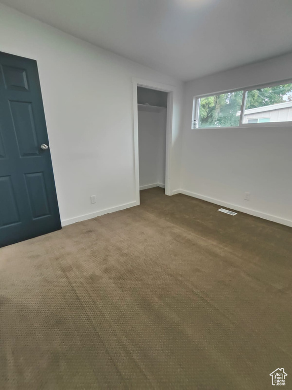 Unfurnished bedroom with dark colored carpet, baseboards, and a closet