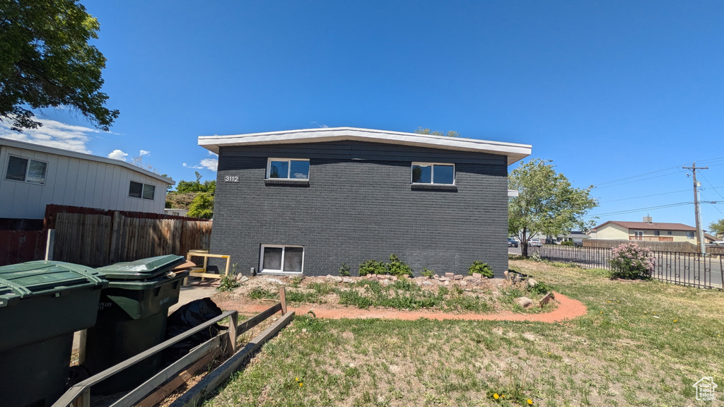 View of side of property featuring a fenced backyard, a yard, a garden, and brick siding