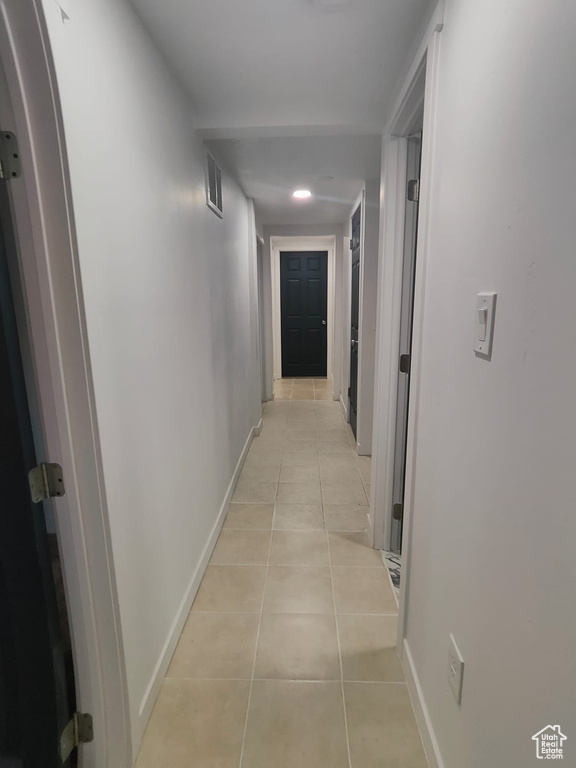 Hall featuring light tile patterned floors, baseboards, and arched walkways