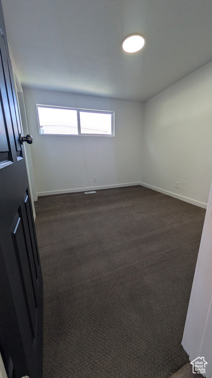 Spare room with plenty of natural light, baseboards, and dark carpet