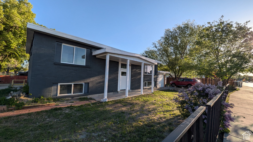 Back of house featuring brick siding, fence, and a yard