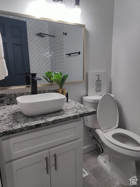 Bathroom featuring toilet, vanity, tiled shower, and tile patterned floors