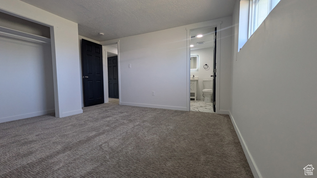 Unfurnished bedroom with carpet floors, baseboards, a closet, and a textured ceiling