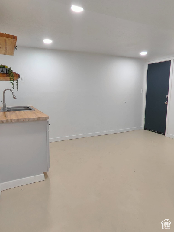 Bar area featuring a sink, recessed lighting, finished concrete flooring, and baseboards