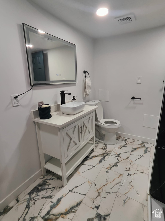 Bathroom featuring baseboards, vanity, and marble look tile flooring