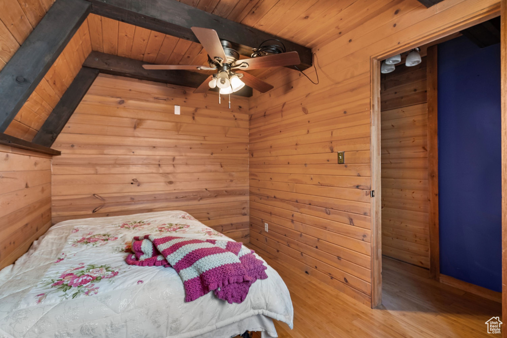 Bedroom featuring wood walls, wood finished floors, wooden ceiling, and beamed ceiling