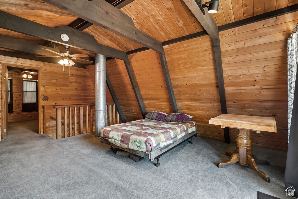 Bedroom with wooden walls, wood ceiling, vaulted ceiling with beams, and carpet