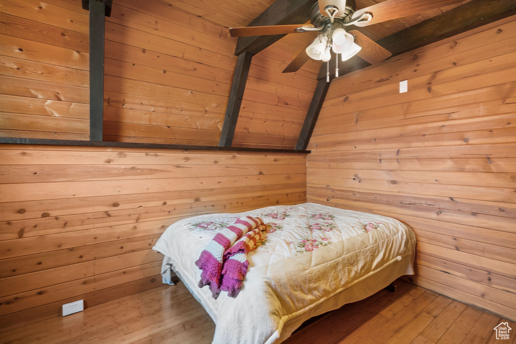 Bedroom featuring wooden walls, beamed ceiling, wood ceiling, and wood-type flooring