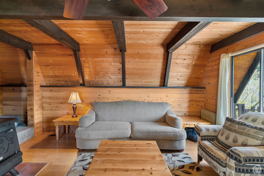 Living room featuring a wood stove, hardwood / wood-style floors, wooden walls, wood ceiling, and lofted ceiling with beams