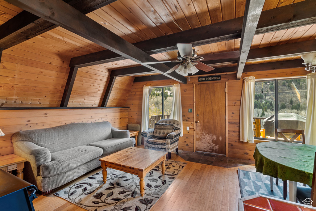 Living room with wood ceiling, ceiling fan, wood walls, and beam ceiling