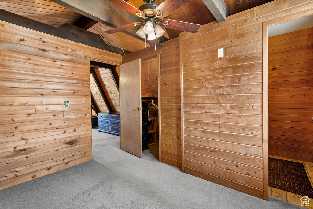 Interior space with carpet flooring, vaulted ceiling with beams, wood walls, and wood ceiling