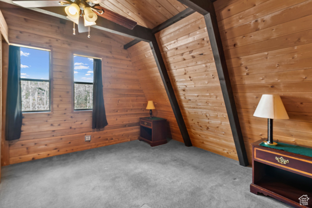 Bonus room with lofted ceiling with beams, a ceiling fan, wood walls, and carpet flooring