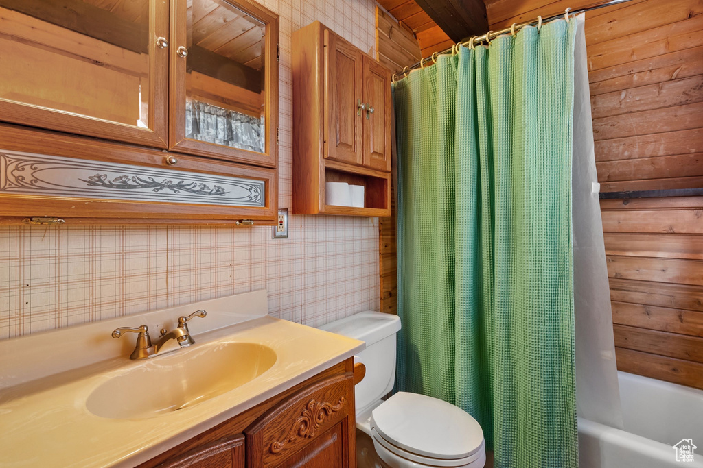 Bathroom featuring vanity, shower / bath combo with shower curtain, toilet, and wallpapered walls