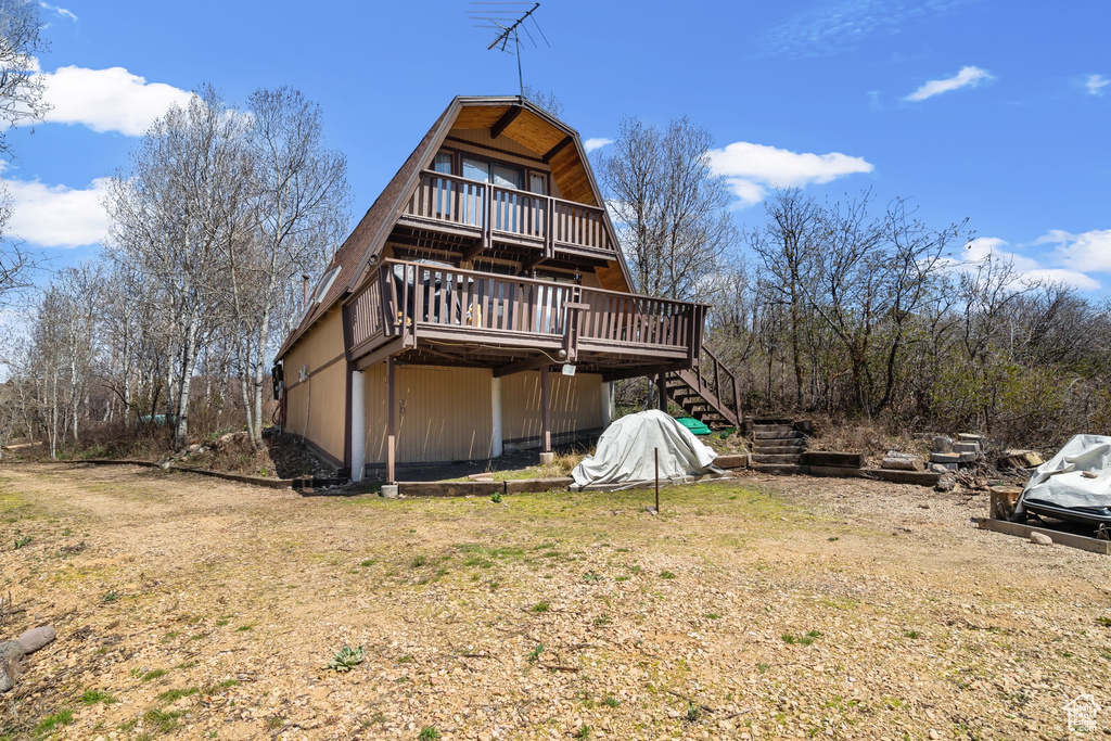 Rear view of house featuring a gambrel roof, a wooden deck, and stairway
