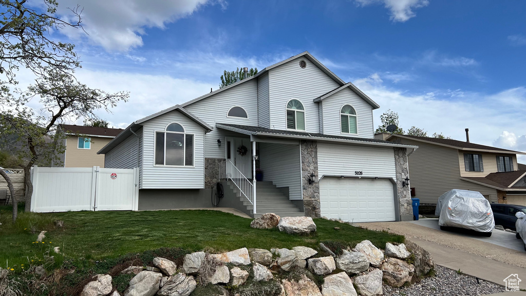View of front of home with concrete driveway, fence, a front yard, and a garage