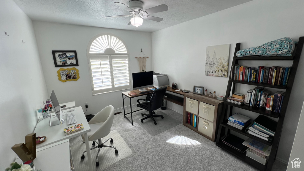 Carpeted home office featuring a textured ceiling, ceiling fan, and baseboards