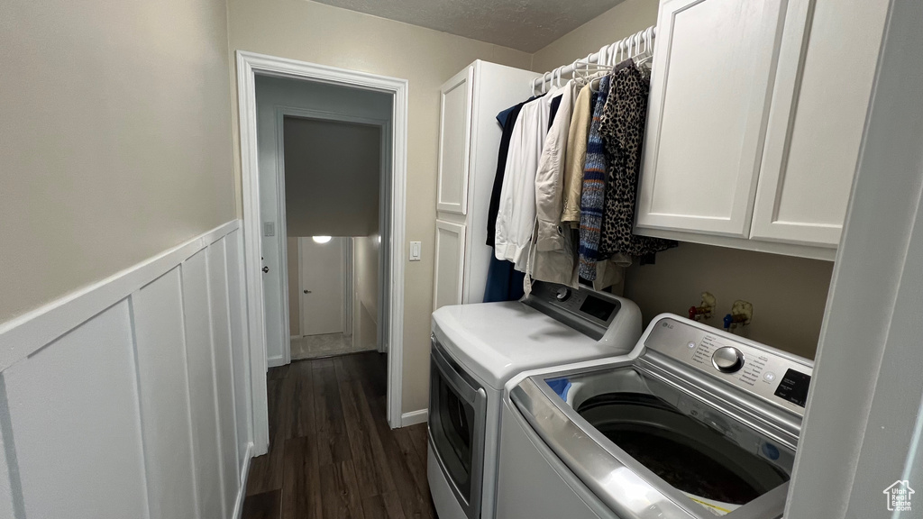 Clothes washing area with washer and clothes dryer, cabinet space, and dark wood-style floors