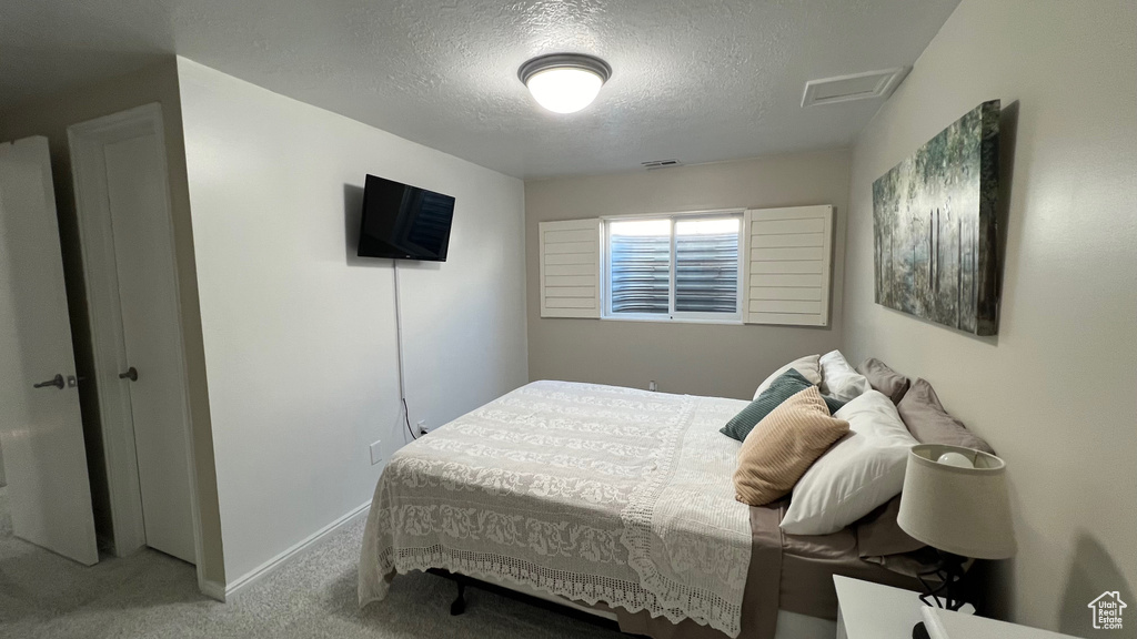 Carpeted bedroom with baseboards, attic access, a textured ceiling, and visible vents