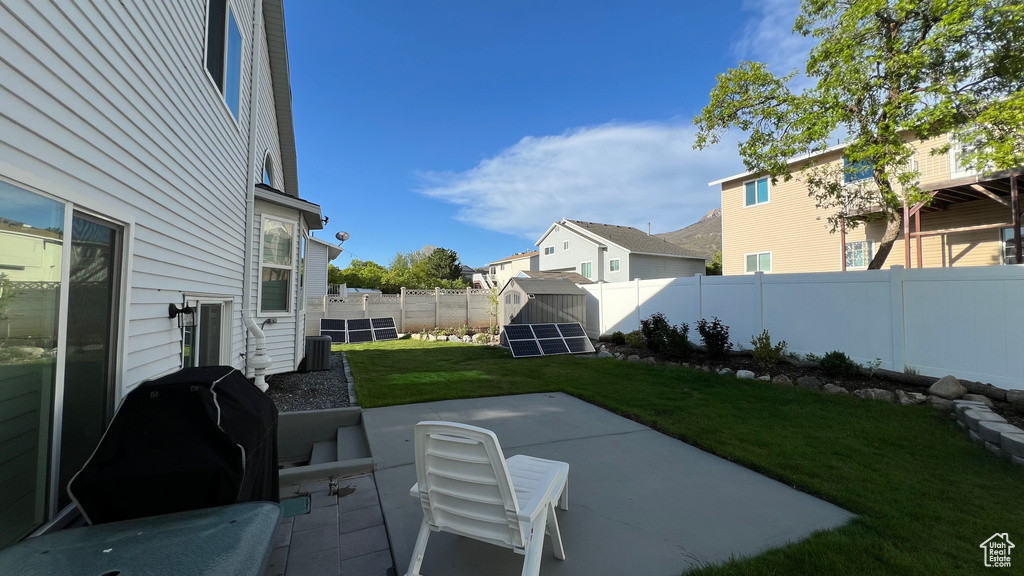 View of patio / terrace with a storage unit, a fenced backyard, and an outbuilding