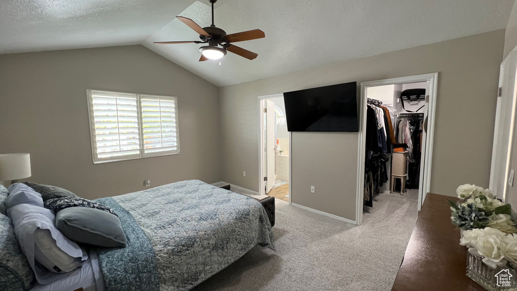 Bedroom with connected bathroom, light colored carpet, vaulted ceiling, a spacious closet, and a closet