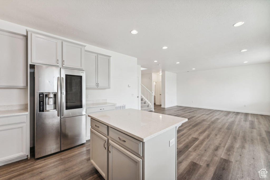 Kitchen featuring a kitchen island, wood finished floors, light countertops, stainless steel fridge with ice dispenser, and recessed lighting