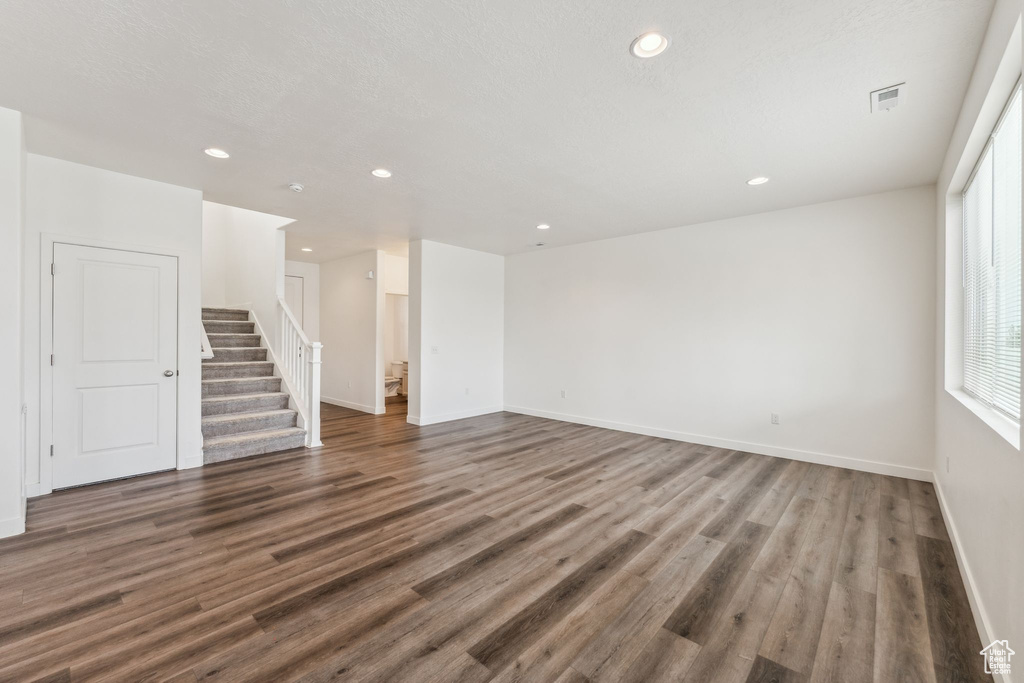 Unfurnished living room featuring recessed lighting, baseboards, stairs, and wood finished floors