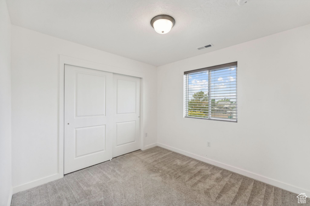 Unfurnished bedroom with baseboards, visible vents, carpet, and a closet