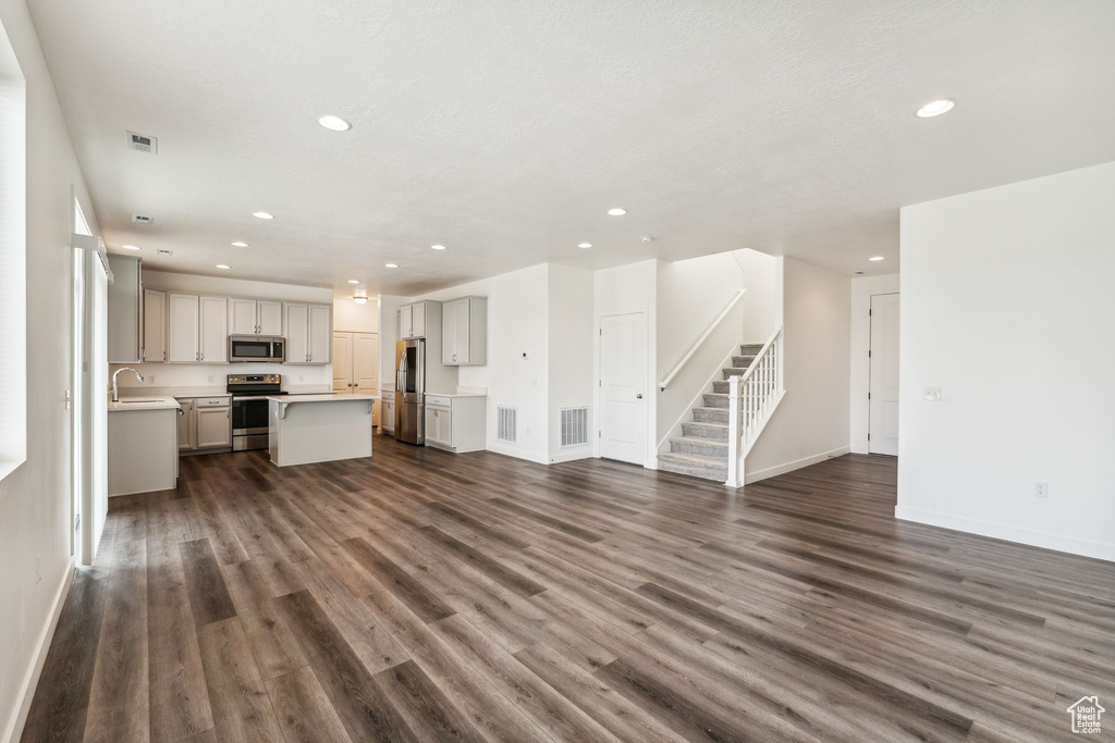 Unfurnished living room with recessed lighting, a sink, and dark wood-type flooring