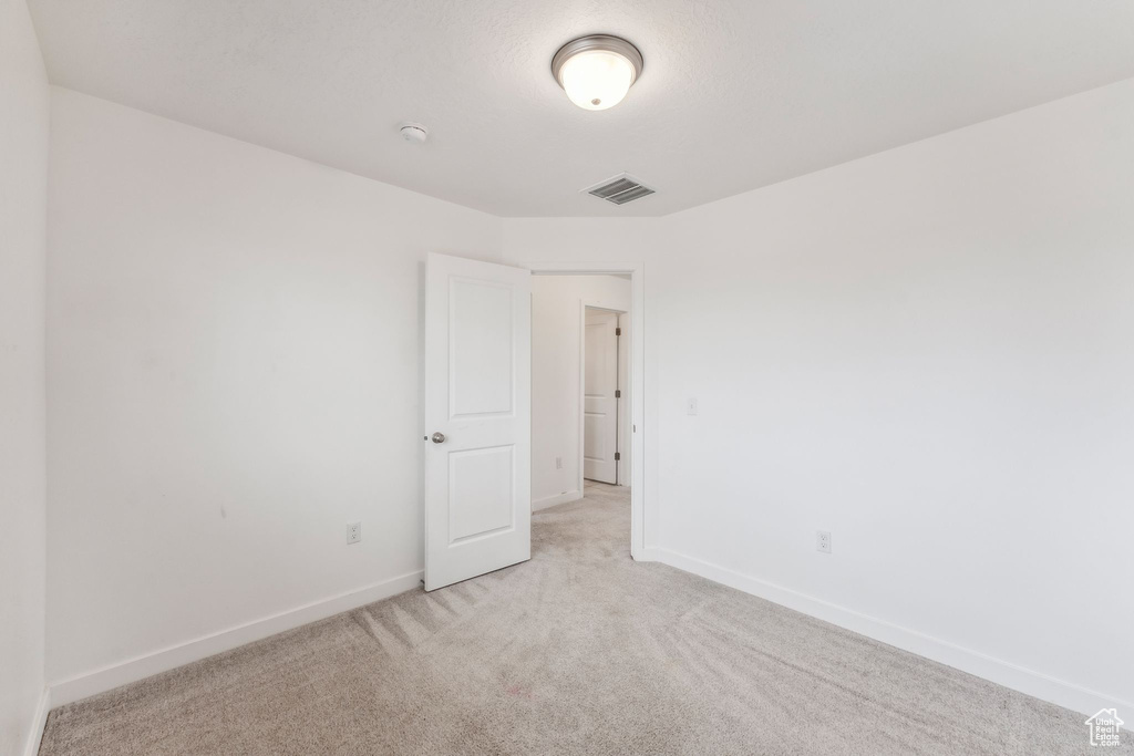 Empty room featuring baseboards, light colored carpet, and visible vents