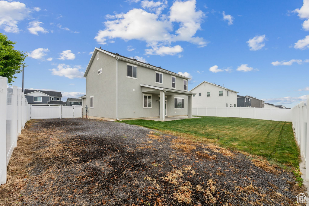 Rear view of property featuring a fenced backyard, stucco siding, a lawn, and a patio area