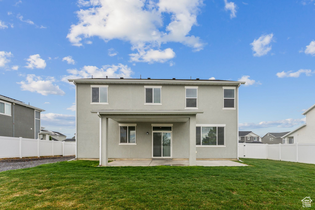 Rear view of property featuring a lawn, a patio, and stucco siding