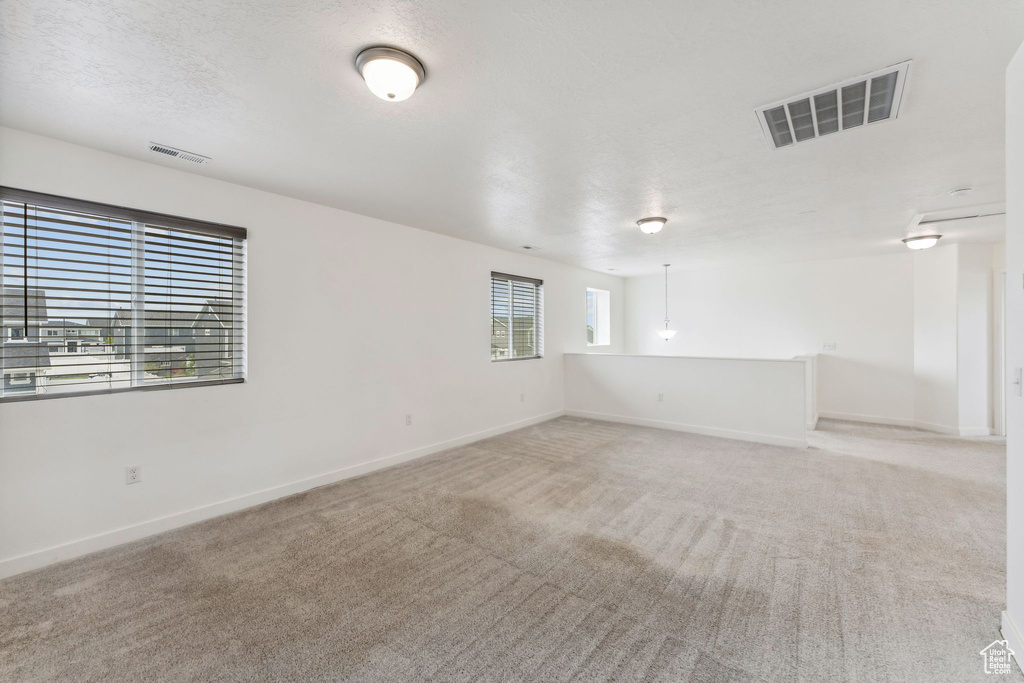 Unfurnished room featuring baseboards, light colored carpet, and visible vents