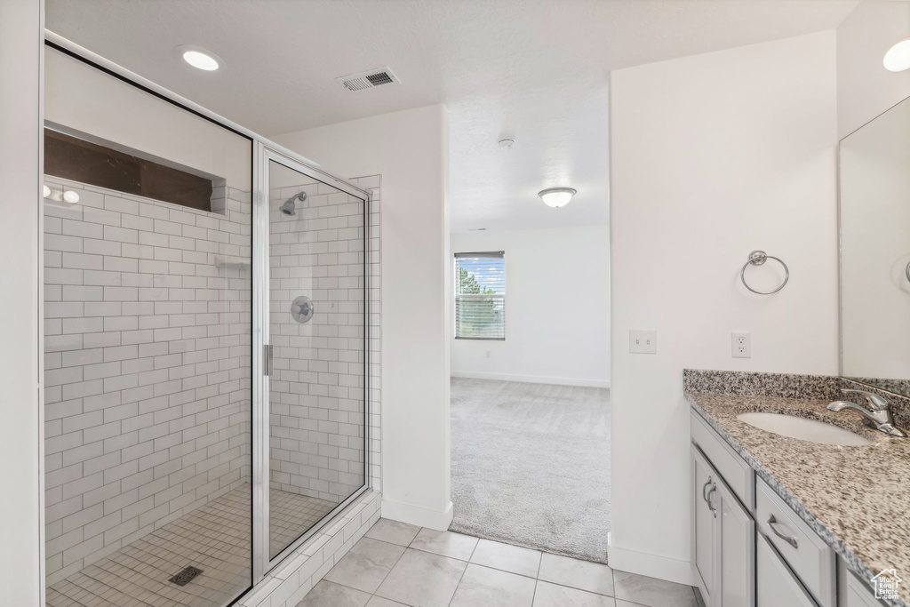 Bathroom featuring visible vents, vanity, baseboards, tile patterned floors, and a stall shower