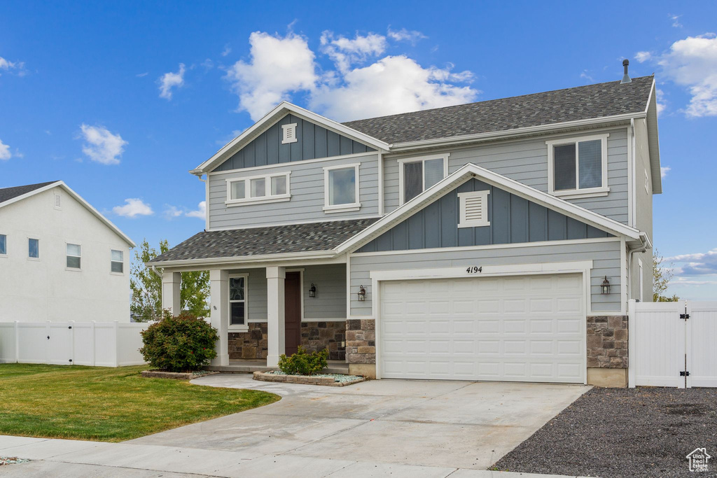 Craftsman house with board and batten siding, fence, concrete driveway, and stone siding