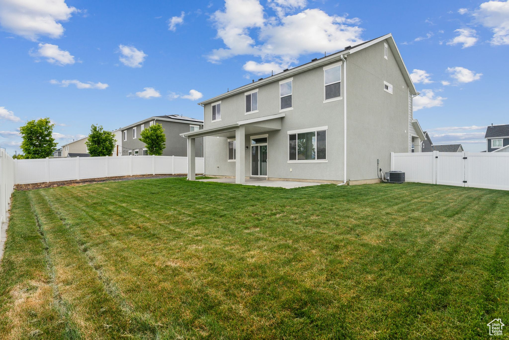 Back of house with a patio area, cooling unit, a fenced backyard, a yard, and stucco siding