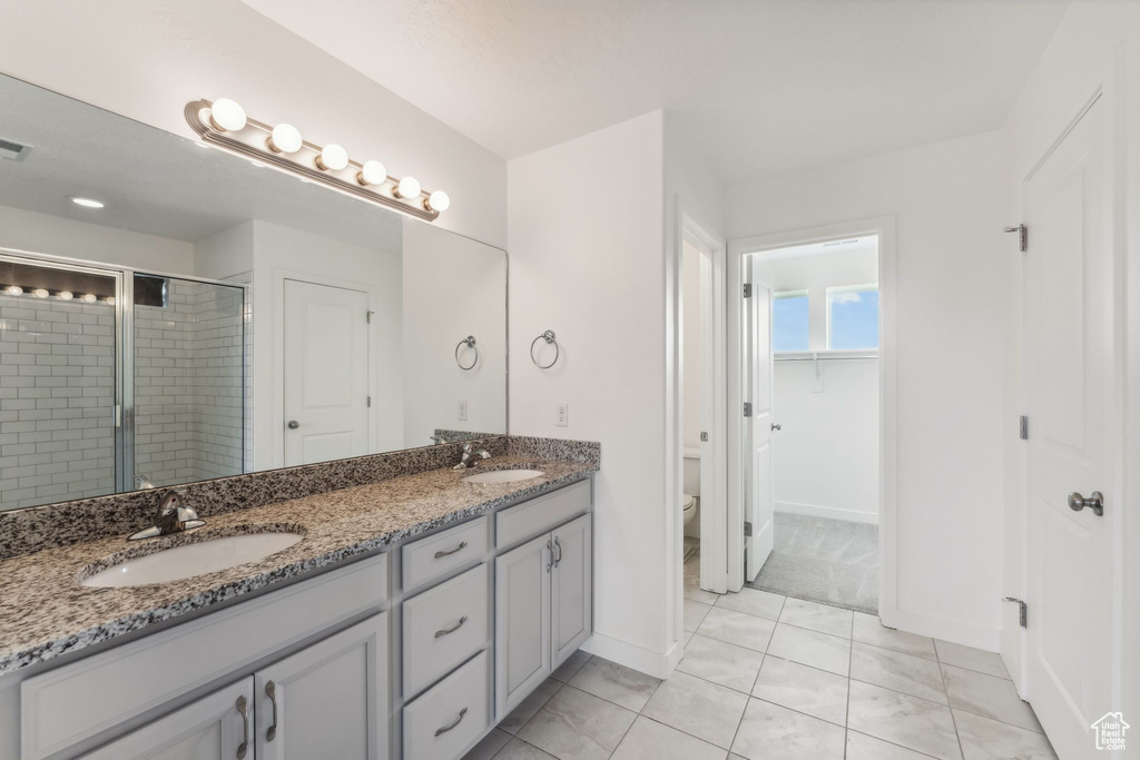Bathroom with a sink, a shower stall, toilet, and double vanity
