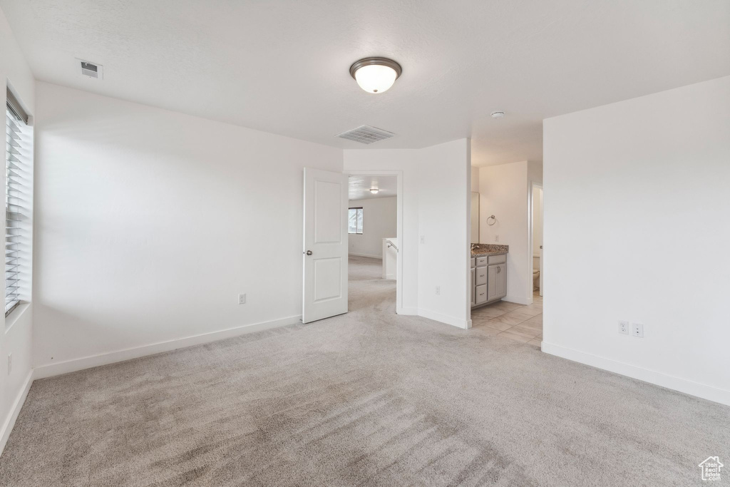 Unfurnished bedroom featuring baseboards, multiple windows, light carpet, and visible vents