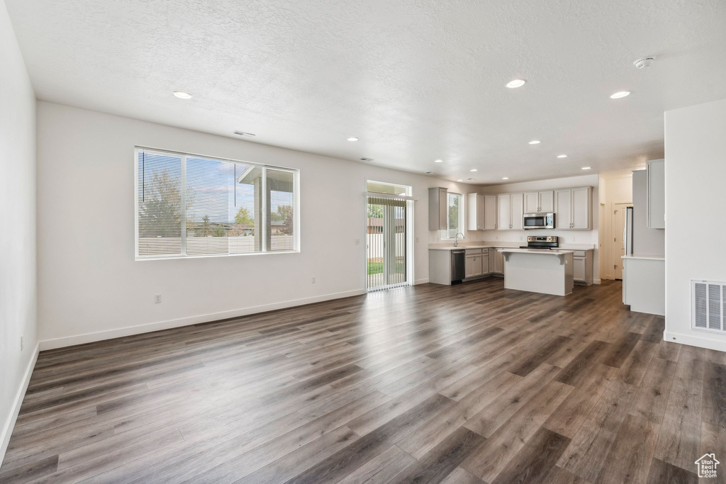 Unfurnished living room with recessed lighting, baseboards, dark wood-style flooring, and visible vents
