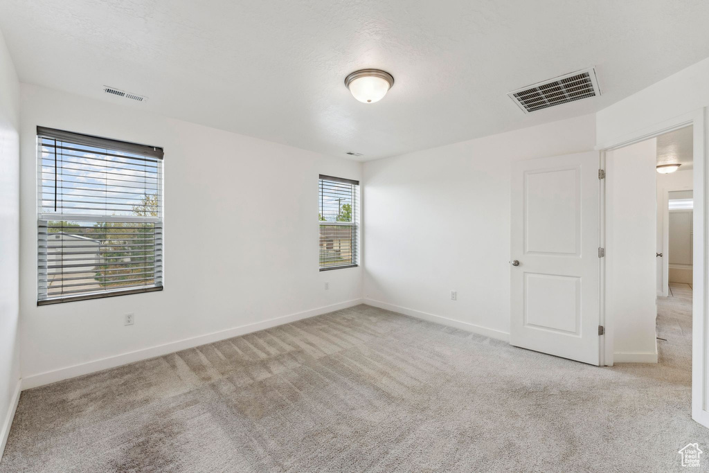 Carpeted empty room featuring visible vents and baseboards
