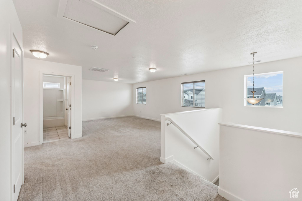 Interior space with baseboards, visible vents, and light carpet