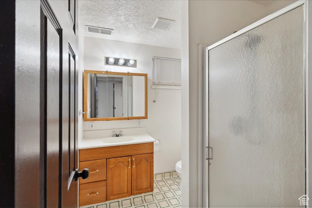 Bathroom featuring a textured ceiling, visible vents, and a stall shower