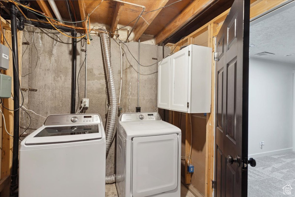 Washroom featuring cabinet space, baseboards, visible vents, and washer and clothes dryer